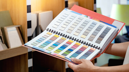 Wall Mural - Designer hand holding sample color swatch catalog in material library. Choosing finishing materials for wall and floor interior architecture or furniture design