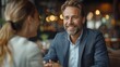 © Vilaysack - Smiling business professionals having a conversation in a modern office setting with warm lighting and positive ambiance.