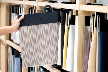 Wall Mural - Designer hand choosing striped beige fabric swatch sample for curtain or drapery design and upholstery furniture. Interior decoration material ideas.