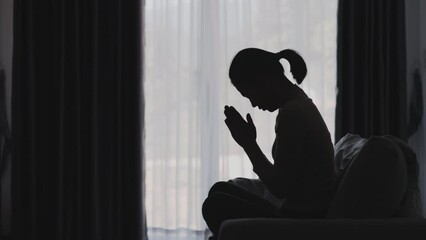 Wall Mural - Silhouette of a woman praying in the house, seek guidance from God through religious prayer. Person woman, turned to God in prayer.