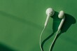 © MDEMRAN - White earphones on green background. Perfect for listening to music on the go