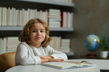 Aufkleber - Child at school. Schoolboy reading book in library. Kids development. Pupil learn to read. Child from elementary school read books in a book store.