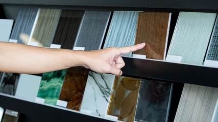Wall Mural - Architect hand choosing and pointing at brown tile material samples on the ceramic collection shelf display in the material library. Designer working for interior architecture project