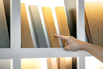 Wall Mural - designer hand choosing and picking wood plank or wooden lumber from display shelf in material librar