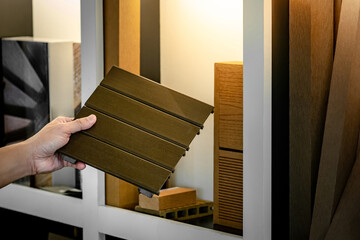 Wall Mural - architect hand choosing and picking outdoor synthetic wood flooring sample from display shelf in mat