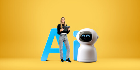 Woman holding a book smiles next to a robot in front of large bl