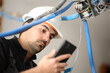 © Antonioguillem - Electrician checking phone installing electrical system