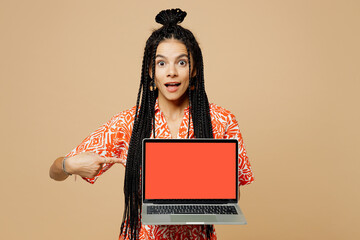 Poster - Young Latin smart IT woman she wear orange casual clothes hold use work point finger on laptop pc computer with blank screen workspace area isolated on plain pastel beige background.Lifestyle concept.