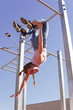 © Westend61 - Carefree woman doing calisthenics hanging upside down from horizontal bars