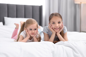 Canvas Print - Cute little sisters on bed at home