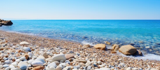 Poster - Rocks scattered along the picturesque Mediterranean coastline, with a stunning view of the sea and a clear blue sky in the background, perfect for a copy space image.