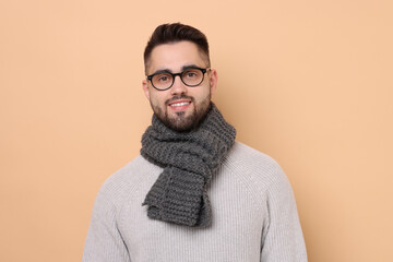 Wall Mural - Smiling man in knitted scarf on beige background