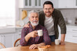 © New Africa - Happy son and his dad at wooden table in kitchen