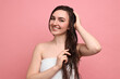 © New Africa - Young woman applying hair mask on pink background