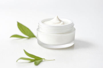 Poster - Closeup of a jar of white cream with green leaves on white background