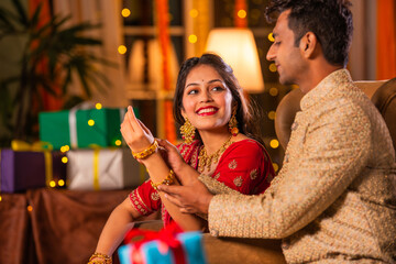 Wall Mural - Indian husband puts gold bangle or bracelet in wife's wrist on diwali festival or anniversary