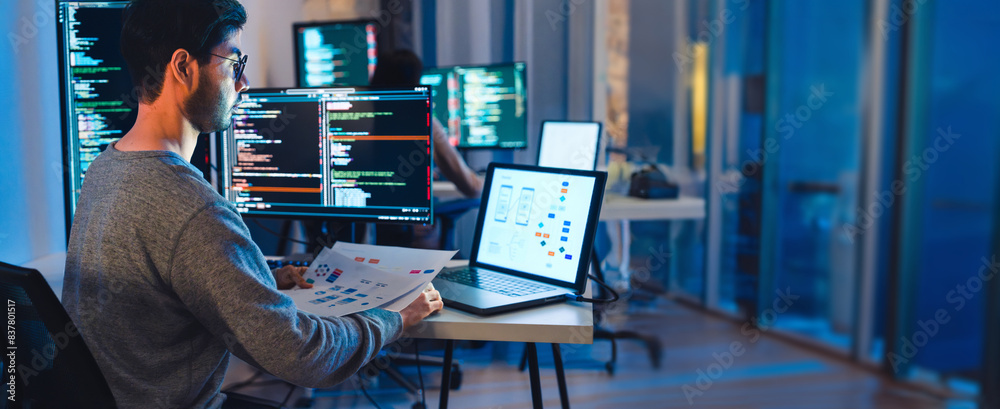 Asian software developers working on multiple screens displaying code ...