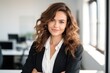 © vefimov - A woman with long brown hair is smiling and wearing a business suit. She is standing in front of a window with a white background