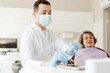 © Maria Vitkovska - Professional attractive male dentist in protective mask, latex gloves holding dental tools