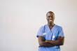 © Maskot - Portrait of confident male doctor with arms crossed in front of white wall