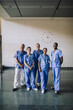 © Maskot - Portrait of smiling diverse healthcare team in blue scrubs standing together at hospital