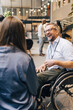© Maskot - Happy male entrepreneur with disability sitting on wheelchair during networking event at convention center