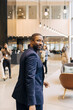© Maskot - Portrait of male entrepreneur looking over shoulder while walking in lobby at convention center