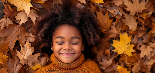 Autumn delight of a little African American girl. Adorable little girl relaxing on antumn leaf bed.