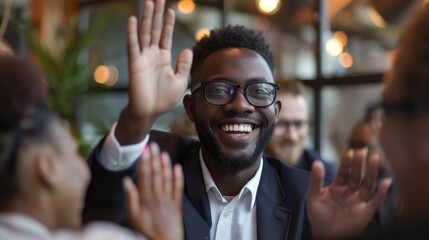 Business team celebrating good results in office meeting. Young black man gives high five to colleague while diverse multiethnic teammates cheer. Teamwork and success concept.