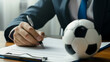 © VK Studio - Professional signing papers with a soccer ball on the desk.