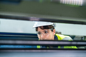 Wall Mural - Male and female engineers in neat work clothes prepare and control the production system of large modern machines in a factory producing industrial technology products.