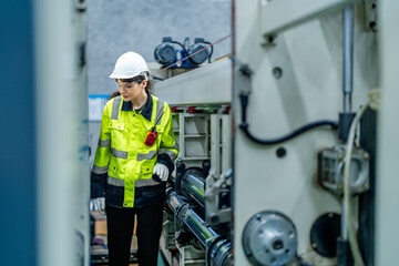 Wall Mural - female engineers in neat work clothes prepare and control the production system of large modern machines in a factory producing industrial technology products.