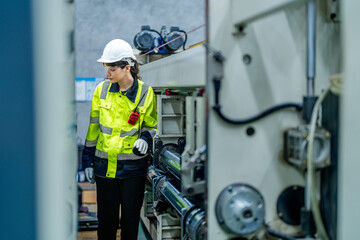 Wall Mural - female engineers in neat work clothes prepare and control the production system of large modern machines in a factory producing industrial technology products.