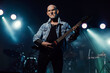 © ysbrandcosijn - Senior rock guitarist with electric guitar in jeans jacket on stage.