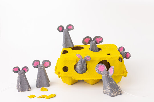 Yellow egg carton creatively repurposed as cheese with mouse figurines peeking out. Gray and pink paper used for mice with tails.