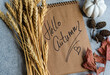 © RooM The Agency - Close-up overhead view of a note pad with words Hello Autumn, ears of wheat, autumn leaves, pumpkin and seeds