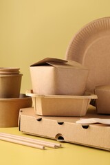 Sticker - Eco friendly food packaging. Paper containers and tableware on pale yellow background