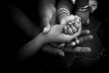 hands of family members holding hands of just born baby shot in black and white- monochrome picture