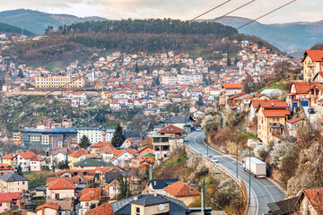Wall Mural - At sunset, Sarajevo's cityscape unfolds, with winding roads weaving through colorful neighborhoods against the backdrop of majestic mountains.