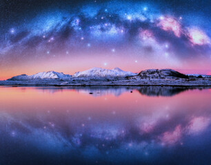 Wall Mural - milky way arch over snowy mountains and sea coast at winter night. panoramic landscape with snowy ro