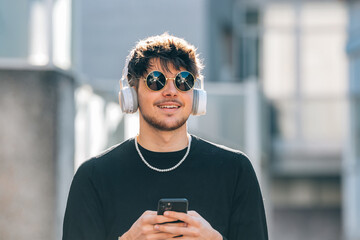 Canvas Print - young man with headphones on the street wearing sunglasses