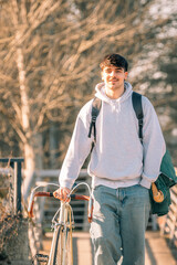 Poster - young man or student on the street with vintage bicycle walking, vertical