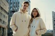 © MD Media - A male and female model wearing plain cream colored hoodies, with streetwear vibes, in a city background