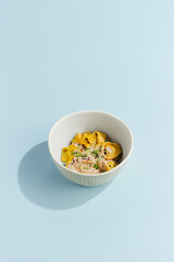 Wall Mural - Delicious Meat Ravioli with Mushroom Sauce in a Stylish Bowl on a Light Blue Background