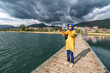 © EdNurg - In Plav, Montenegro, tourists enjoy the tranquil beauty of the lake from the pier, with breathtaking mountain views and clear reflections in the water.