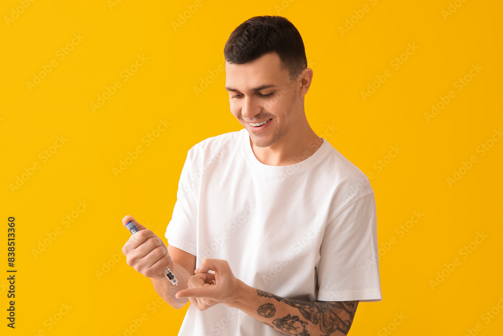 Diabetic young man using lancet pen on yellow background