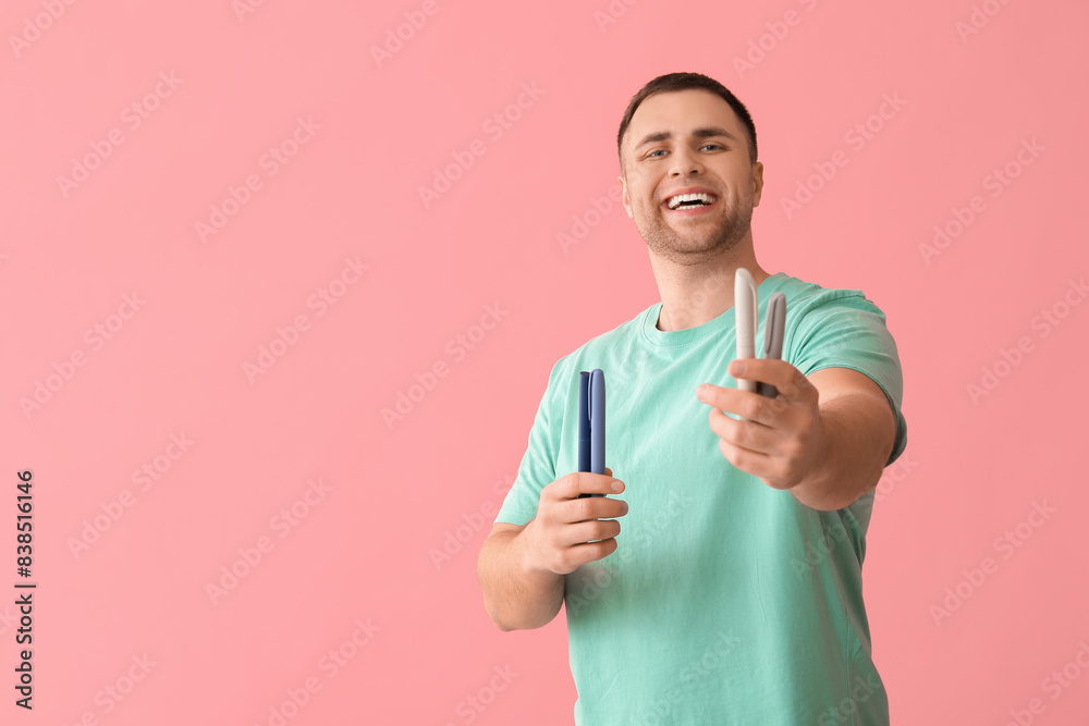 Handsome young happy diabetic man with lancet pens on pink background