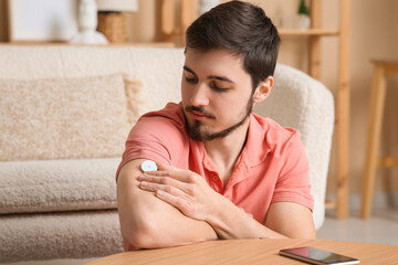 Wall Mural - Diabetic young man with glucose sensor at home, closeup