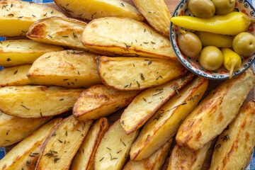 Wall Mural - Oven baked potato wedges served with pickled peppers and olives.
