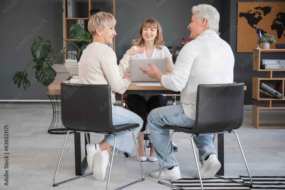 Female travel agent with mature couple working at table in office